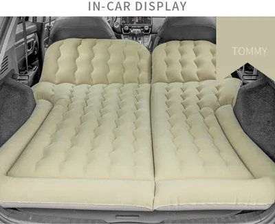 An inflatable mattress is set up in the back of a car, filling the space between the front and back seats.