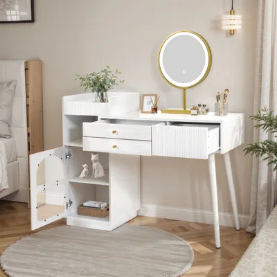 A white vanity table with a lighted mirror, drawers, and an open cabinet, set in a bedroom with a bed and a rug.