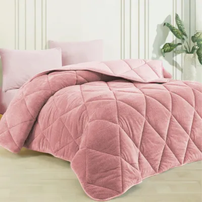 A pink comforter is laid out on a bed with two pink pillows behind it. The background is a wall with vertical white stripes.