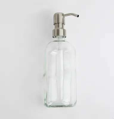 A clear glass soap dispenser with a silver pump head is shown against a white background.