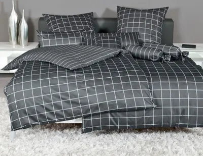A neatly made bed with a grid-patterned duvet cover and pillows.