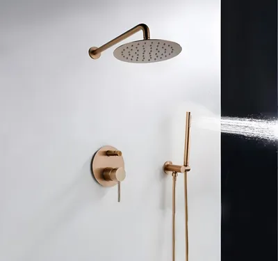 A rose gold shower set mounted on a white wall, with water spraying from the handheld showerhead.