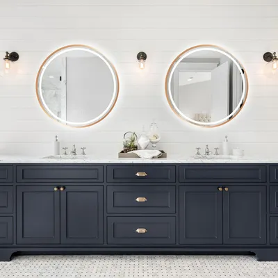 A modern bathroom vanity with two round mirrors above.