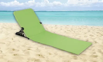 A green beach mat is laid out on a sandy beach with the ocean and sky in the background.