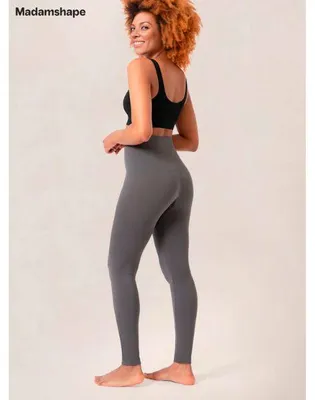 Frau trägt hoch taillierte graue Leggings und einen schwarzen Sport-BH, posiert mit einer leichten Drehung zur Seite
