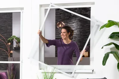 A woman is installing a window screen.