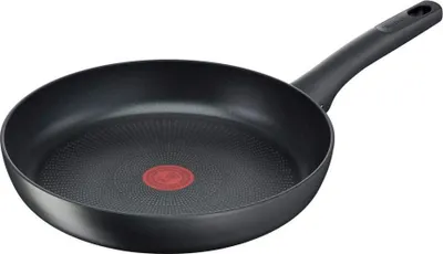 A black frying pan with a red heat indicator in the center, shown from a slightly elevated side angle against a white background.