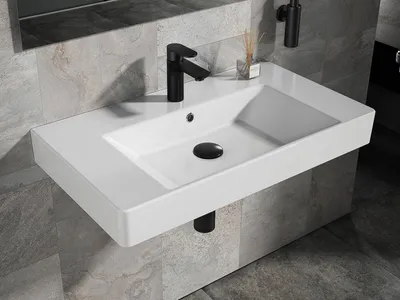 A modern white ceramic washbasin with a black faucet and drain, mounted on a tiled wall.