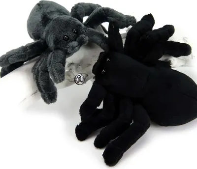 Two plush toy spiders, one gray and one black, are positioned on a white surface.