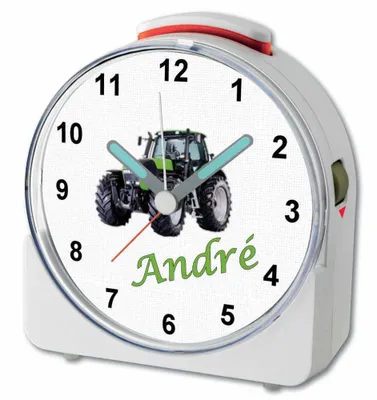 A close-up of a white alarm clock with a tractor image and the name 'André' on the face.