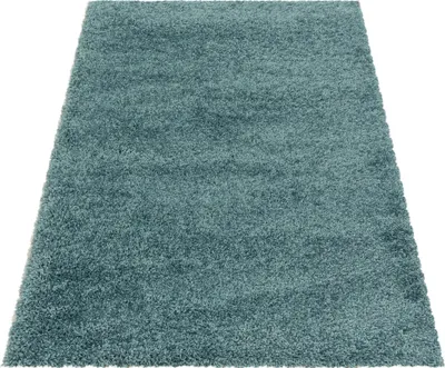 A close-up, angled view of a blue shaggy rug on a white background.