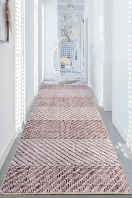 A long hallway with a runner rug and a hanging chair.