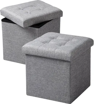 Two grey storage ottomans are shown against a white background. One ottoman is slightly open, revealing its interior.