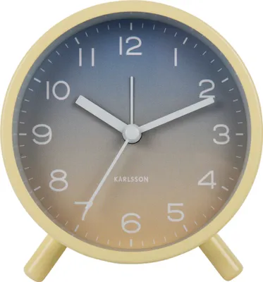 A close-up, front-facing view of a yellow analog alarm clock with a gradient dial.