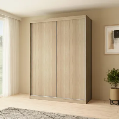 A wardrobe with sliding doors in a room with a window and curtains.