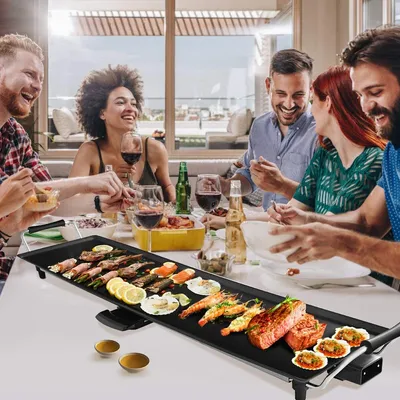 A group of friends enjoying a meal together around a table with a grill.