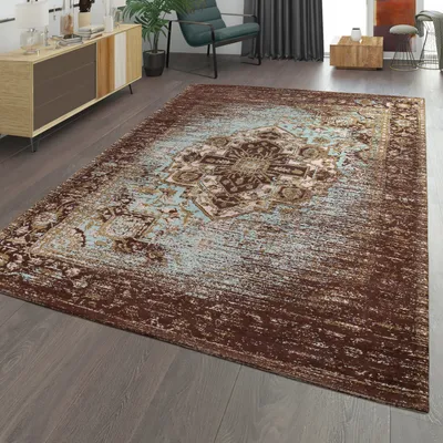 A rug is placed on a wooden floor in a living room setting, with a cabinet and chair in the background.