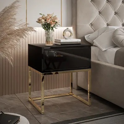 A modern bedroom setting with a black high-gloss nightstand with gold legs.