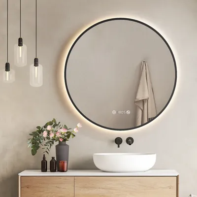 A modern bathroom vanity with a round LED mirror, sink, and decorative items.