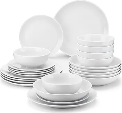 A collection of white ceramic plates and bowls are neatly stacked and arranged on a white background.