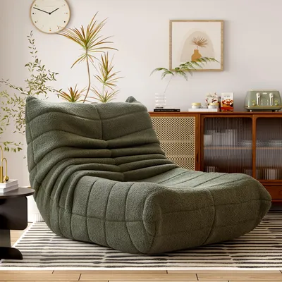 A green beanbag chair is placed on a striped rug in a living room setting, with a cabinet and decor in the background.