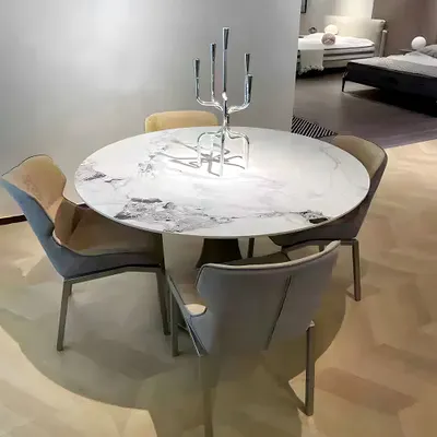 A round dining table with chairs in a showroom setting.