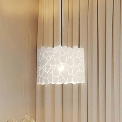 A white pendant lamp with a patterned shade hangs in front of beige curtains.