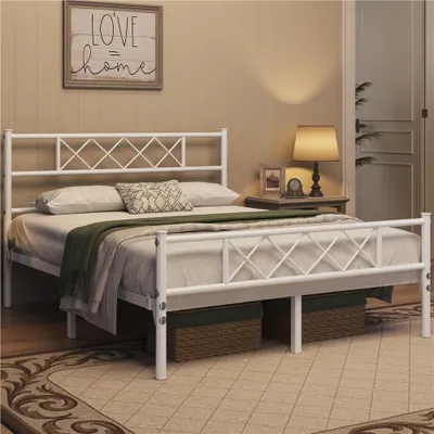 A bedroom scene featuring a white metal bed frame with a diamond pattern headboard and footboard, dressed with bedding and a green throw blanket. A bedside table with a lamp and decorative items is visible to the right.