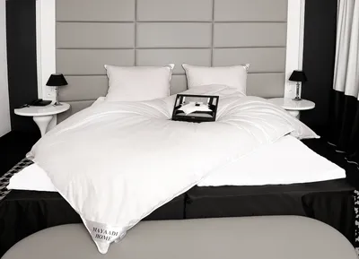 A neatly made bed with white bedding and a headboard.