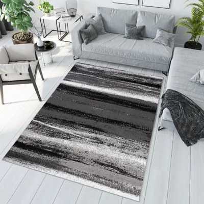 A modern living room with a grey sofa, a chair, and a rug.