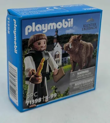 A Playmobil box featuring a monk and a wild boar in front of a monastery.