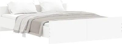 A white bed frame with white pillows and a gray and white striped blanket.