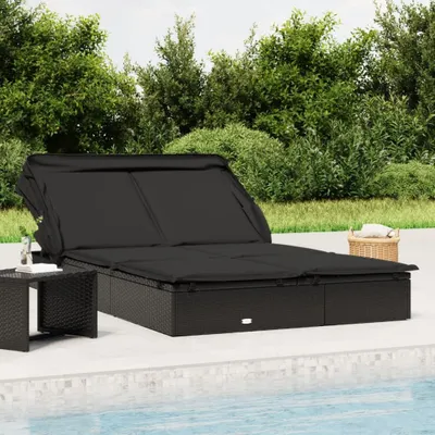 A black rattan sun lounger with a canopy is placed on a patio next to a swimming pool.