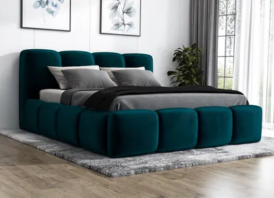 A dark green upholstered bed with a mattress and pillows, placed on a rug in a room.