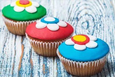Produktbild von Wallario Premium Glasbild, freischwebende Optik, kräftige Farben, Größe 90 x 60 cm Motiv Bunte Muffins - alter Holztisch - Stillleben