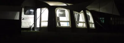 A caravan awning at night with lights on inside.