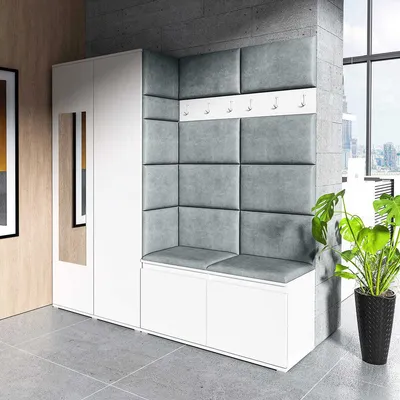 A modern hallway or entrance area featuring a white wardrobe with a mirror, a corner bench with upholstered gray cushions, and a coat rack above the bench. A large potted plant is visible to the right, and a window with a city view is in the background.