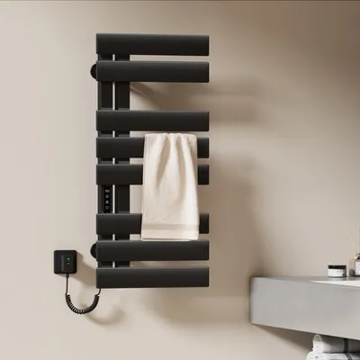 A black electric towel warmer mounted on a light-colored wall next to a concrete sink.