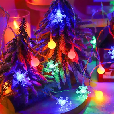 Christmas lights on miniature trees with a candle in the background.