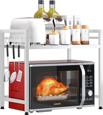 A white metal kitchen rack holding a microwave, a red appliance, and various kitchen items on its shelves.
