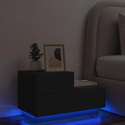 A black nightstand with LED lighting is placed next to a bed in a dimly lit room.