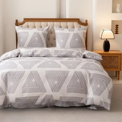 A neatly made bed with white bedding featuring a geometric triangle pattern in gray.