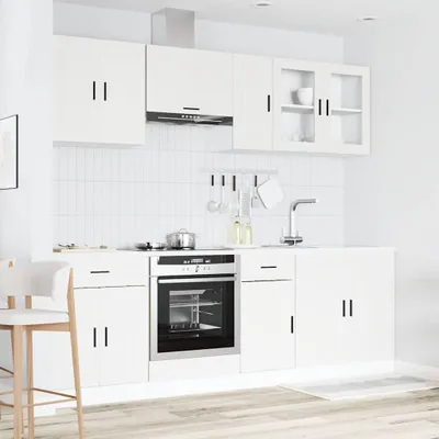 A modern white kitchen with cabinets, an oven, and a sink.