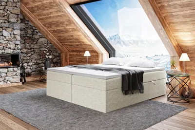 A cozy bedroom scene in a rustic attic with a large window overlooking a snowy mountain landscape.