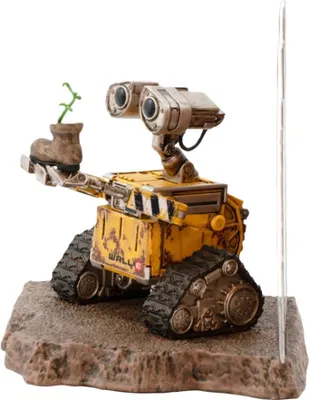A Wall-E figurine holding a plant in a boot, standing on a textured base.