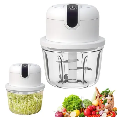 Two white electric mini choppers are shown, one with a clear glass bowl filled with chopped green vegetables, and another larger one with an empty clear glass bowl and visible blades. A basket of fresh vegetables is in the foreground.