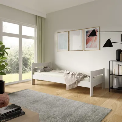 A bedroom scene with a white bed, rug, and large window.