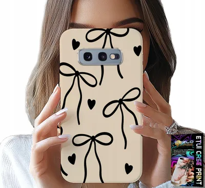 A person is holding a phone case with a bow and heart pattern in front of their face.