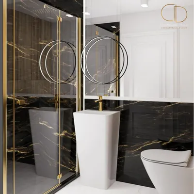 A modern bathroom with black marble tiles, a white pedestal sink, and a toilet.