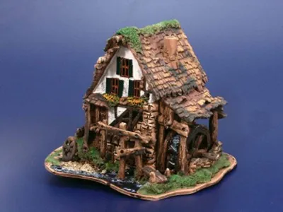 Alte Wassermühle ein malerisches Gebäude mit Moos bewachsen und einem Wasserrad. Farbe warm-erdig.